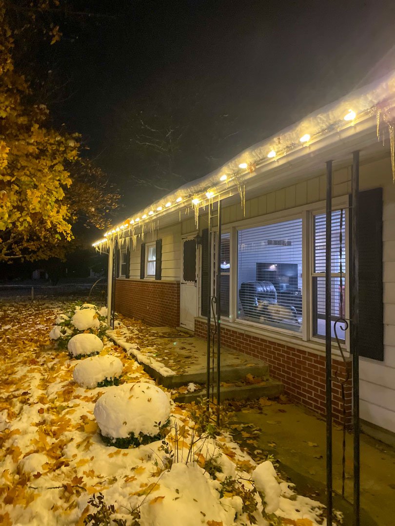 Warm white Christmas lights along the eaves of a brick home